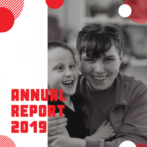2019 Annual Report - Photo of a young woman with a fringe holding a small boy with vision impairment. Both are laughing.