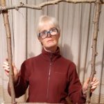 Woman with short blonde hair holding a frame made out of sticks