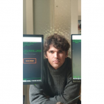 A man framed between two computer screens