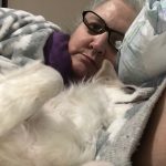 Woman lying down with a fluffy white dog