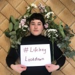 Someone framed by long stem flowers holding a sign saying #LifelongLockdown