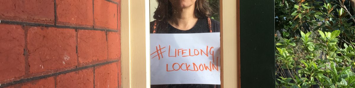 Woman standing in a window holding a #LifelongLockdown sign