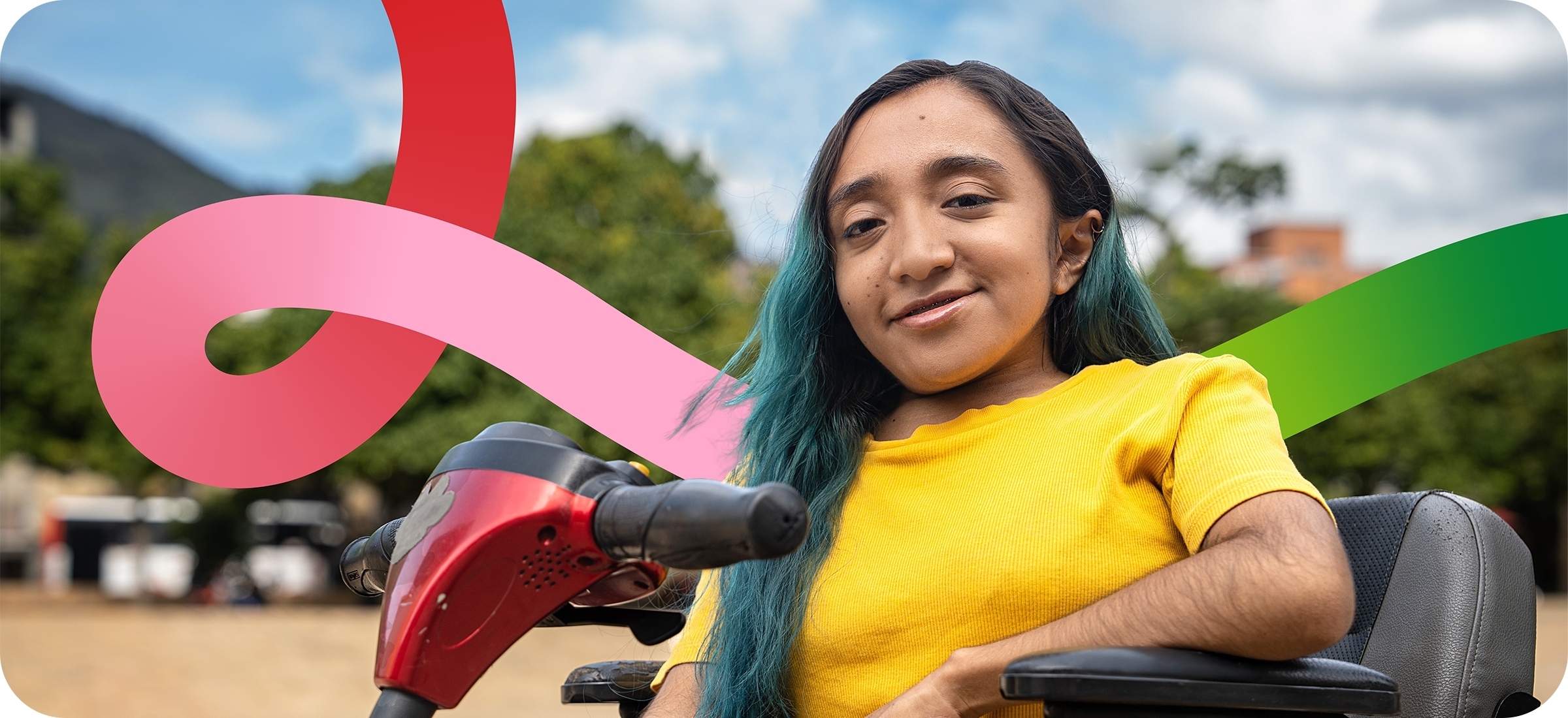 Photo of a person with brown skin, and long black hair with teal streaks sits in a red and black mobility scooter, with one arm positioned on the arm rest. They have a slight smile on their face. In the background, you can see trees and blue sky, as well as swirls with gradients of red, pink and green to match the DRC logo and branding.