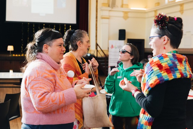 Four people in brightly coloured clothing having a conversation
