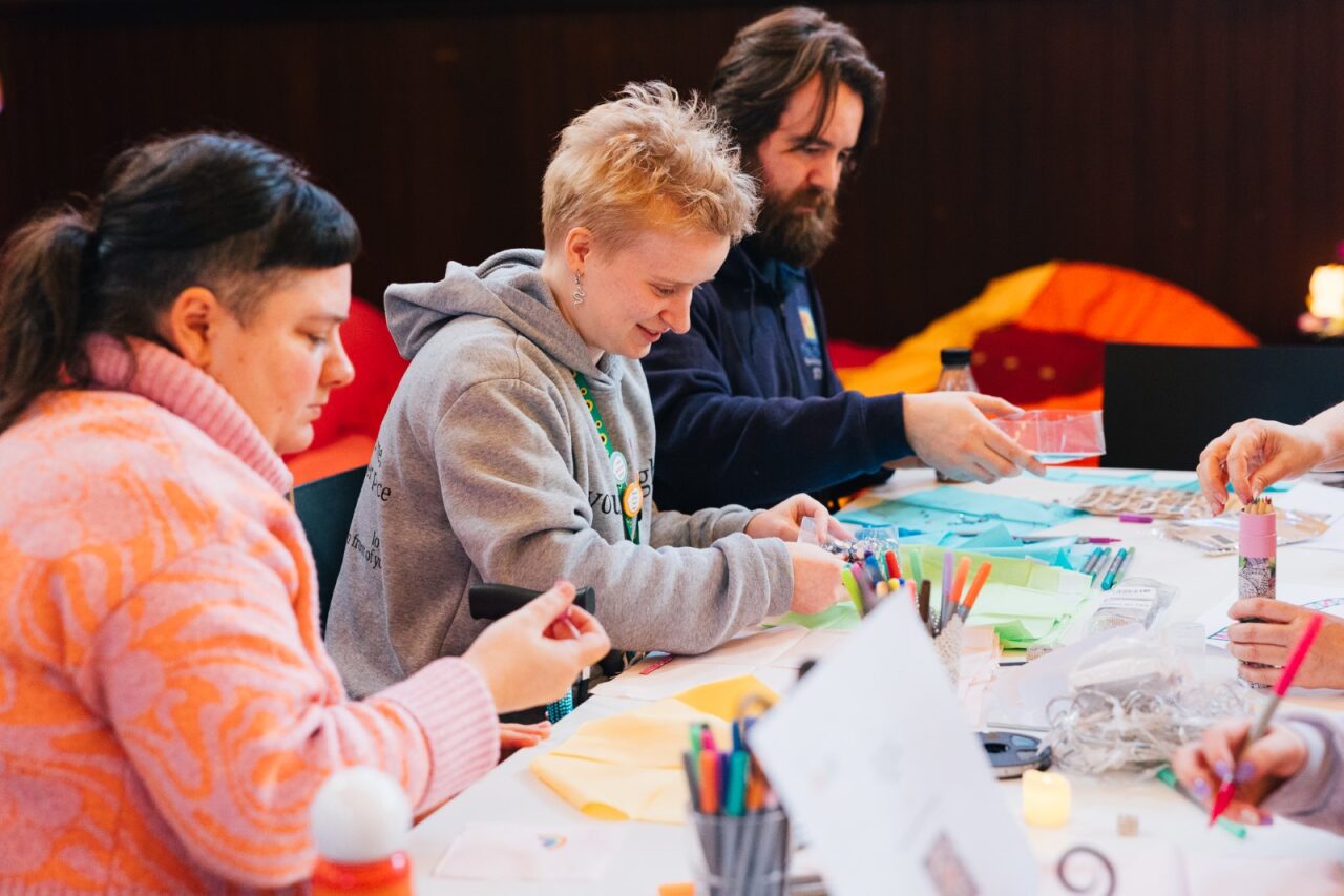 Three people doing arts and crafts as a long table